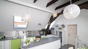 Una cocina moderna con una isla central, armarios verdes e iluminación colgante.