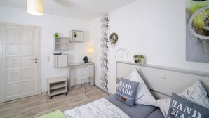 Un dormitorio moderno con cama, mesitas de noche, un escritorio y una silla.