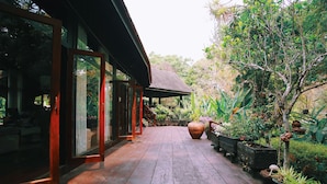A wooden deck with potted plants and a glass-enclosed area. - Villa Darakorn (Chiang Rai)