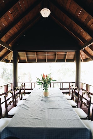 A covered dining area with a long table, chairs, and a potted plant. - Villa Darakorn (Chiang Rai)