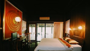 A hotel room with a bed, a desk with a computer, a chair, a large window, and a door leading to an outdoor area. - Villa Darakorn (Chiang Rai)