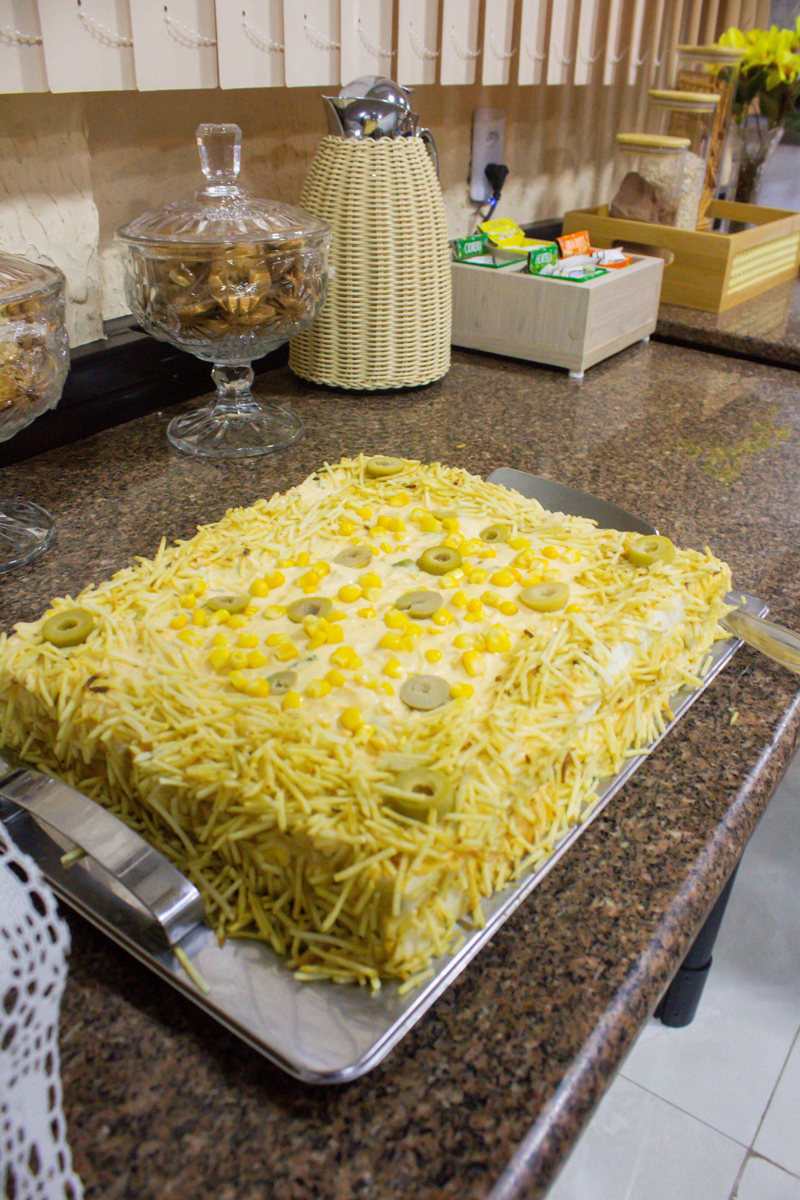 A kitchen counter with a tray of food covered in shredded cheese and corn kernels.