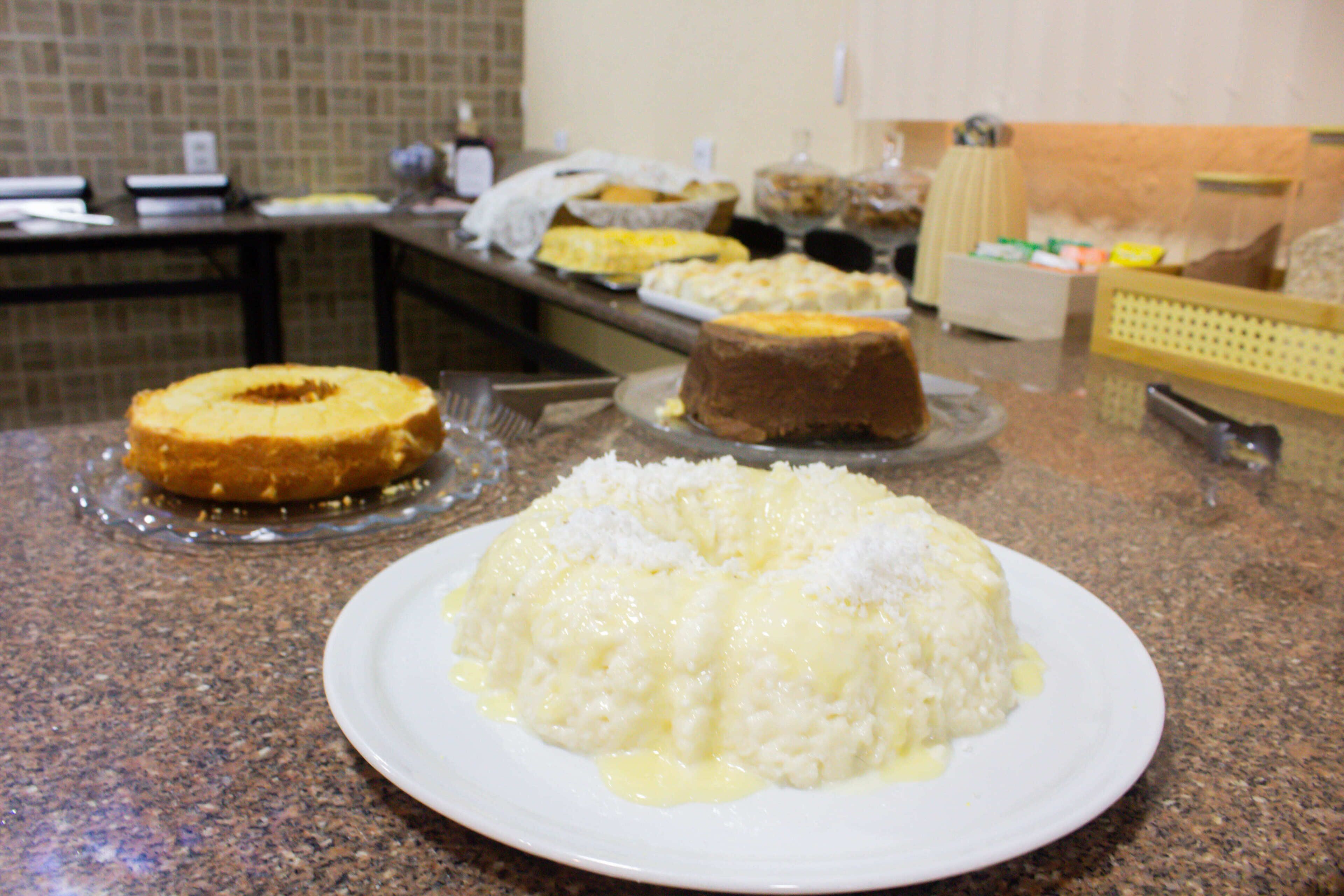 Un bufé con diversos platos, incluyendo arroz, pan y un pastel, sobre una encimera de granito.