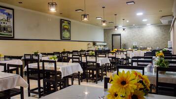 Ein Restaurant mit mehreren Tischen und Stühlen, einige davon mit Sonnenblumen geschmückt.