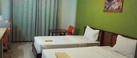 Habitación de hotel con dos camas, un escritorio, una silla y un cuadro en la pared.