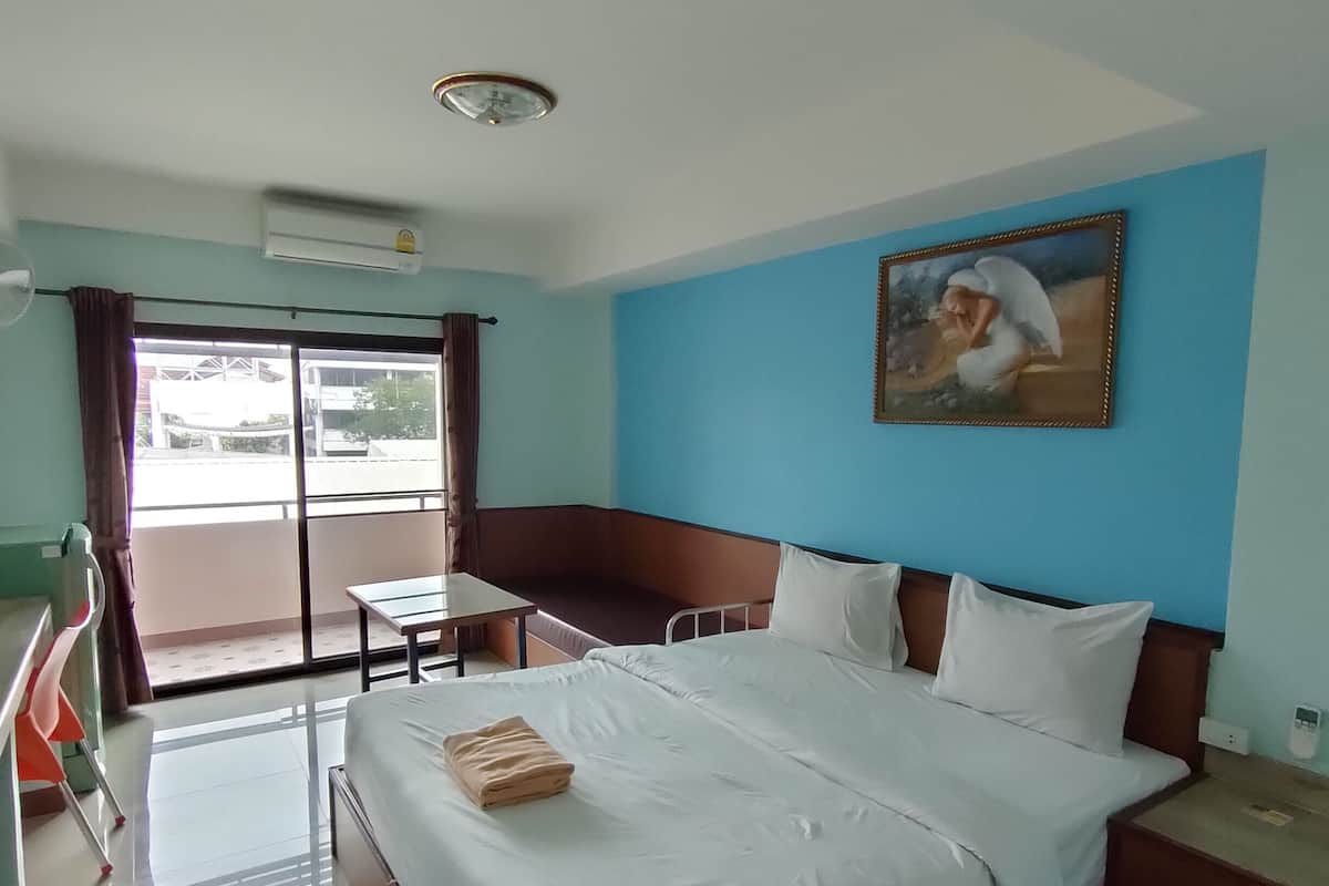 Una habitación de hotel con una cama grande, un escritorio, una silla y un ventanal con cortinas.