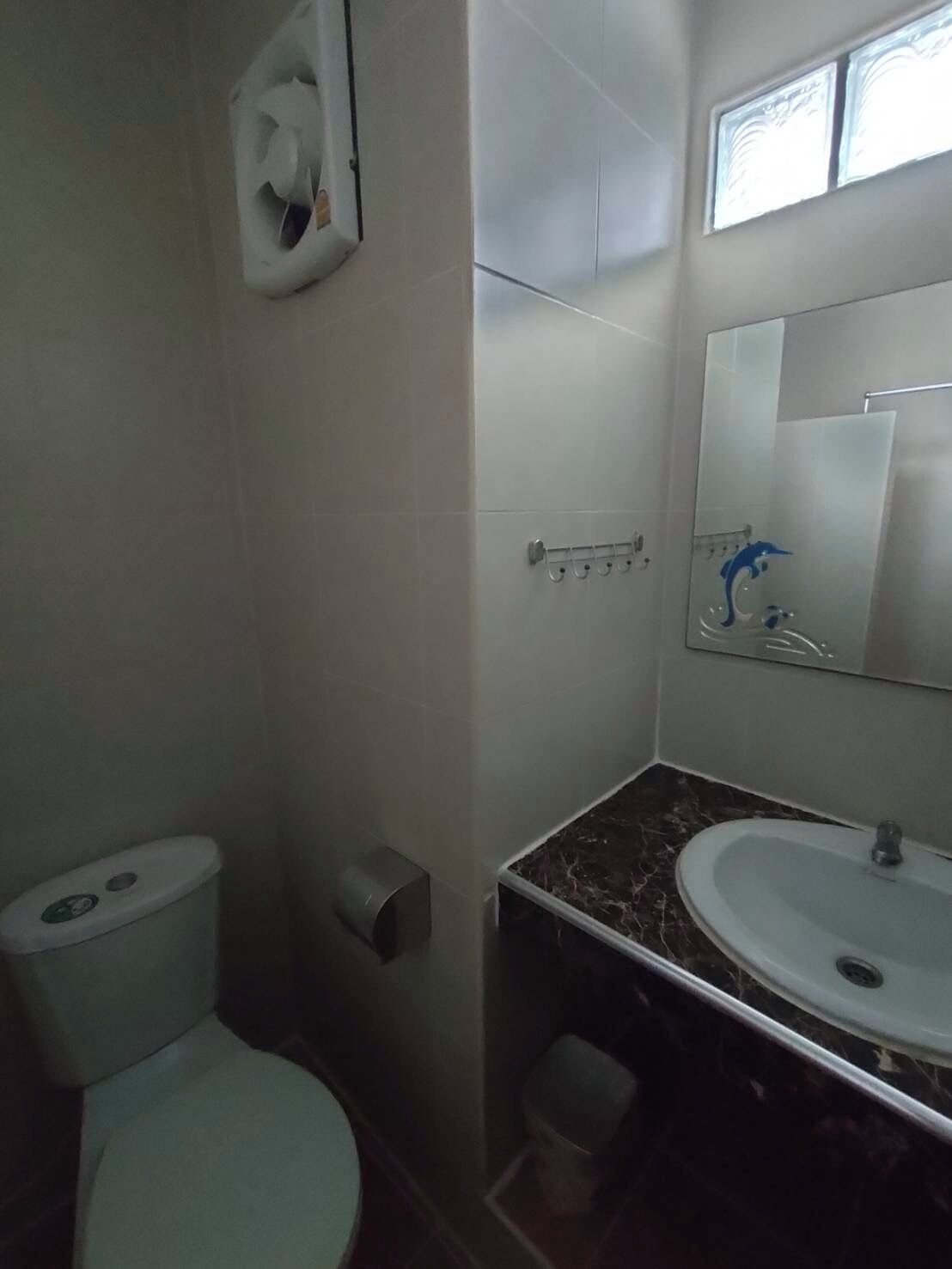 Une salle de bain équipée de toilettes, d’un sèche-mains, d’un lavabo et d’un miroir.