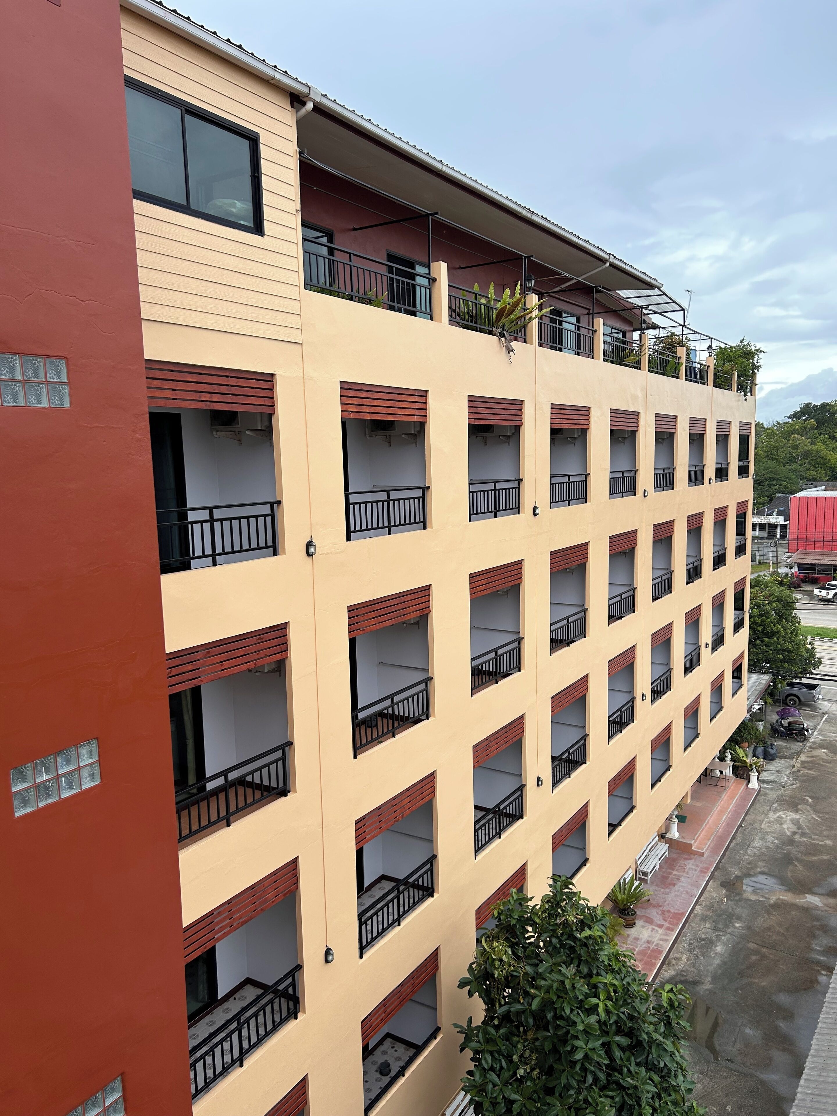 Un immeuble à plusieurs étages, doté de balcons et d’une façade rouge, sous un ciel dégagé.