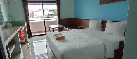 Una habitación de hotel con cama, una mesita, una silla, una ventana con cortinas y un cuadro en la pared.