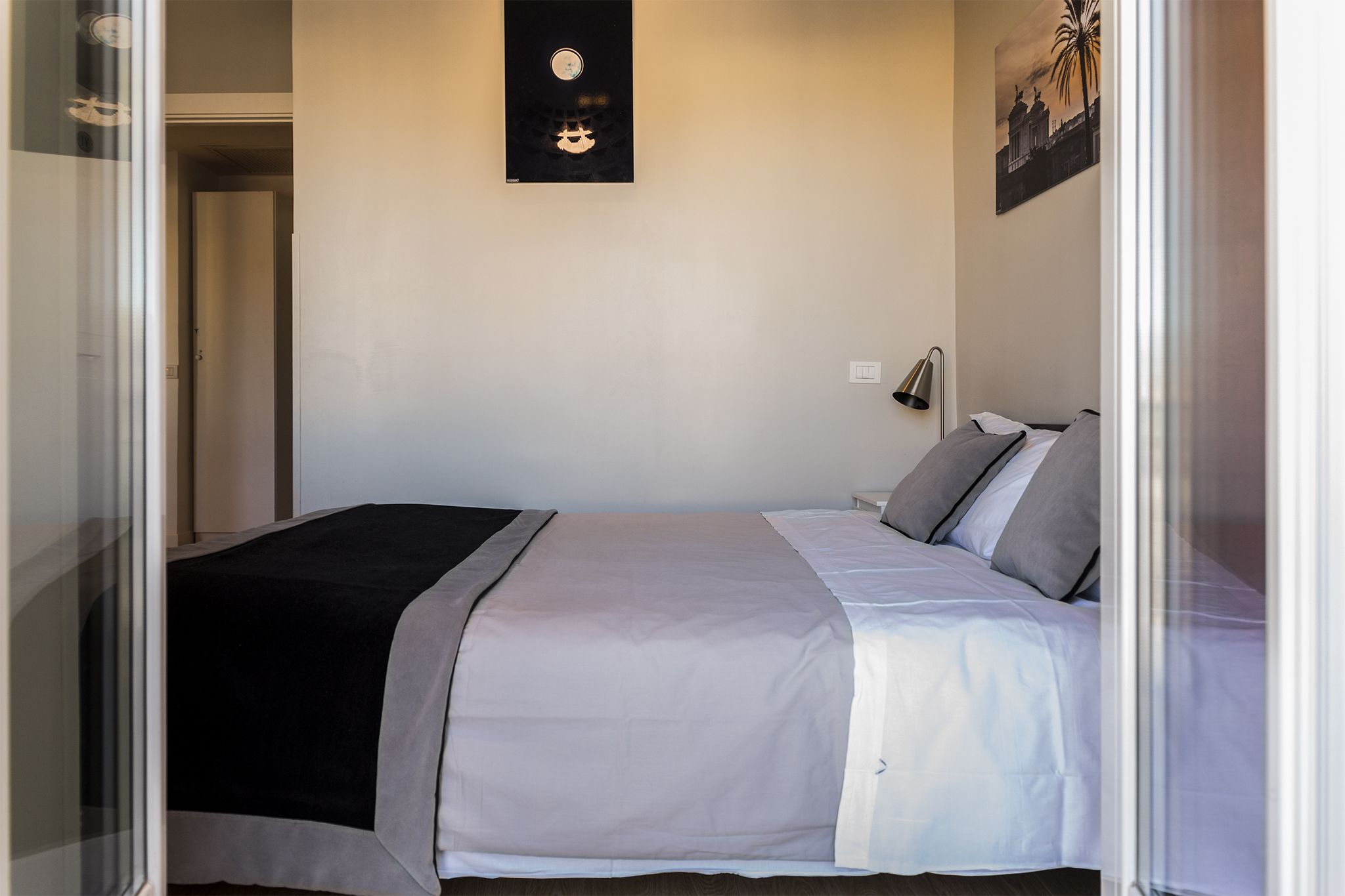 A hotel room with a bed, a nightstand, a wall clock, and a painting.