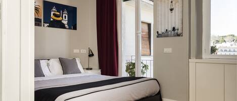 Un dormitorio con cama, mesita de noche, lámpara, ventana con vistas y obras de arte en las paredes.