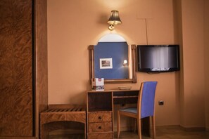 A room with a wooden desk, a chair, a television mounted on the wall, and a lamp. - Hotel Las Moreras (Sariegos)