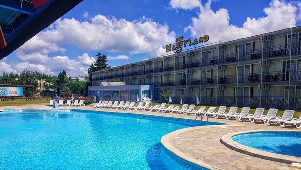 Ein Hotel namens "Haappyland" mit Schwimmbad, Liegestühlen und einem mehrstöckigen Gebäude mit Balkonen.