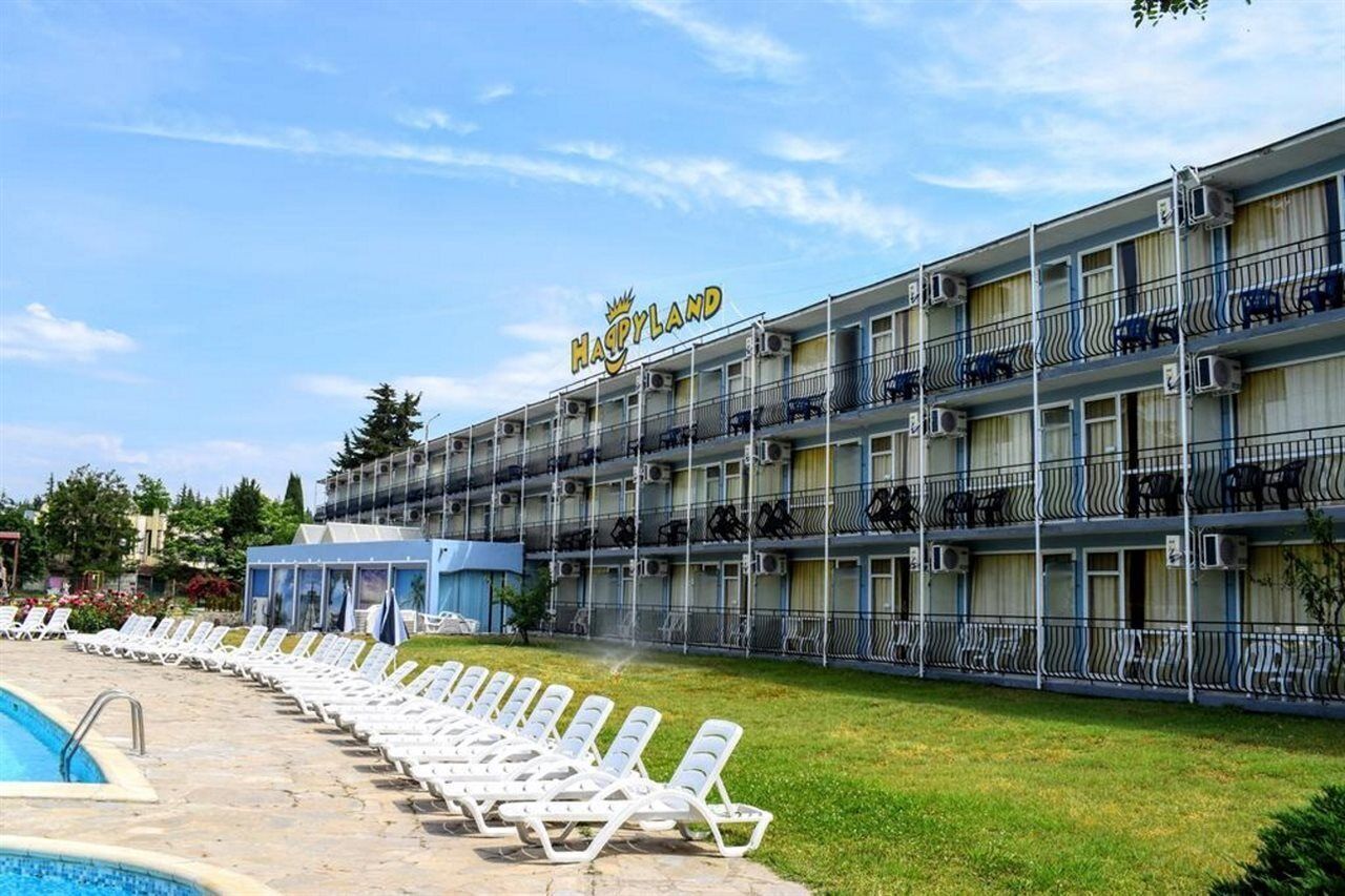 A hotel named "HAPPYLAND" with a pool area and lounge chairs.