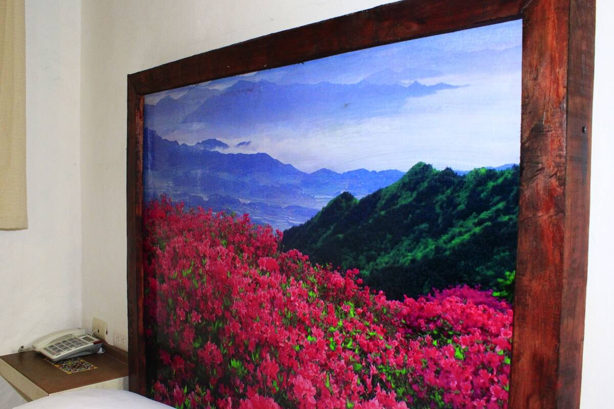 A room with a large painting of a mountainous landscape with pink flowers.