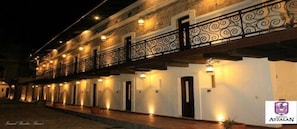 A hotel with a long corridor, multiple doors, and a balcony with decorative railings.