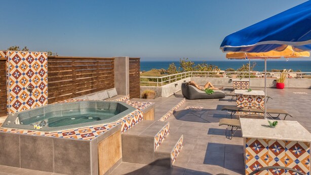 Une terrasse sur le toit avec un jacuzzi, des sièges extérieurs et une vue sur la mer.