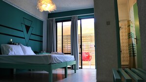 Une chambre à coucher avec un lit, un banc, une chaise rouge et une vue sur l’extérieur grâce à une porte coulissante.