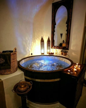 A hot tub with a wooden frame, a wicker basket, and a candle holder.