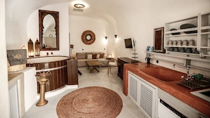A compact kitchen with a central island, a built-in sink, and a dining area with a sofa and coffee table. - Dandy Cave Villa-Private Luxurious Waterfall Pool - Hot Tub (Santorini)