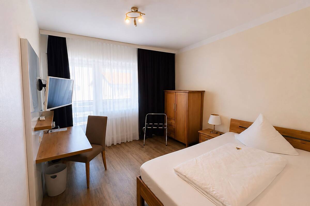 Une chambre d’hôtel équipée d’un lit, d’un bureau, d’une chaise, d’une armoire et d’un téléviseur.