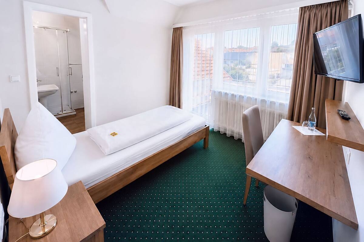 Une chambre d’hôtel comprenant un lit, un bureau, une chaise, une télévision, une lampe et une salle de bain.