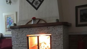 A fireplace with a stone facade and a wooden mantel. - Pousada Bariloche (Teresópolis)