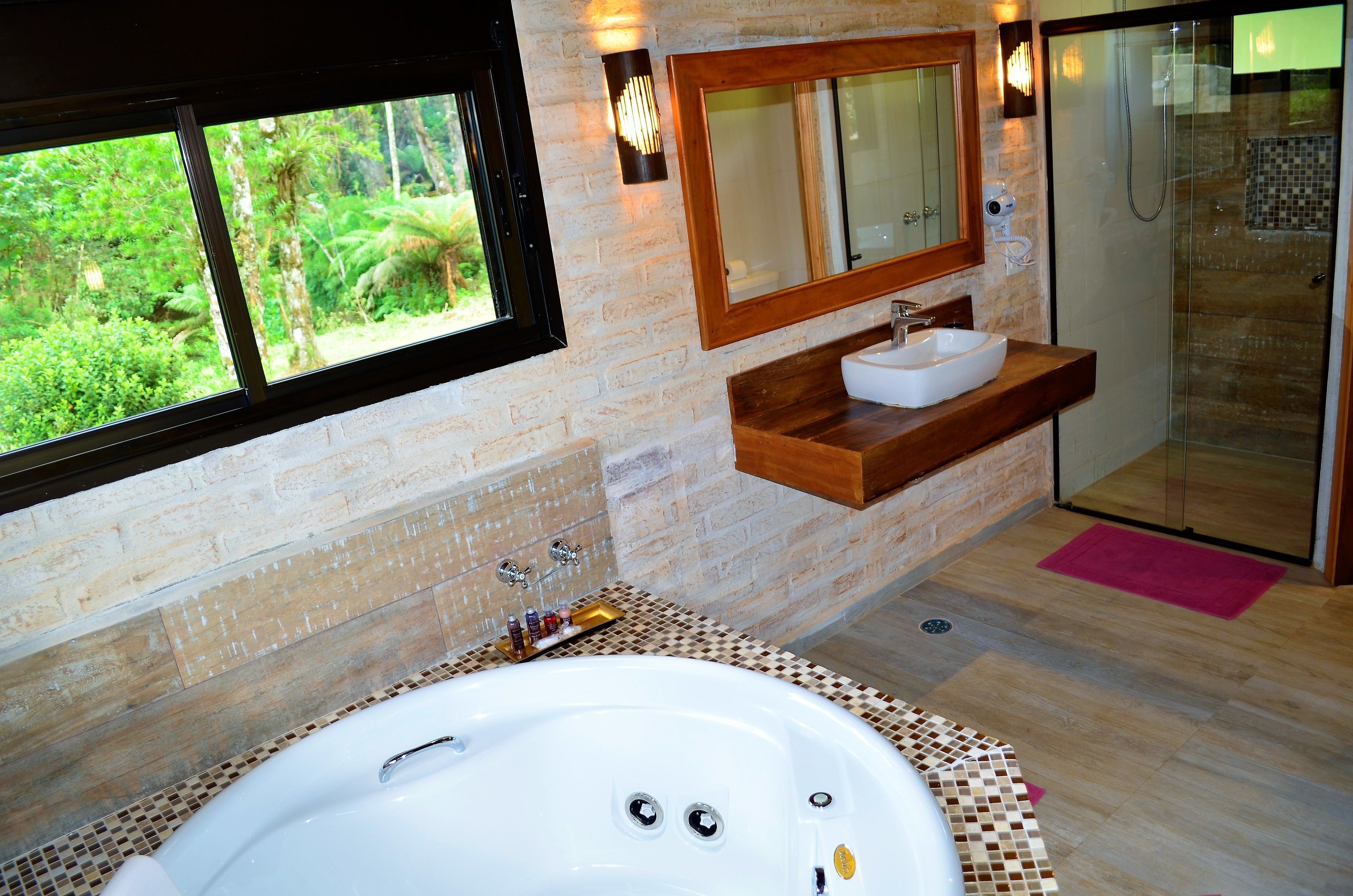 A bathroom with a large bathtub, a sink, a mirror, and a shower.