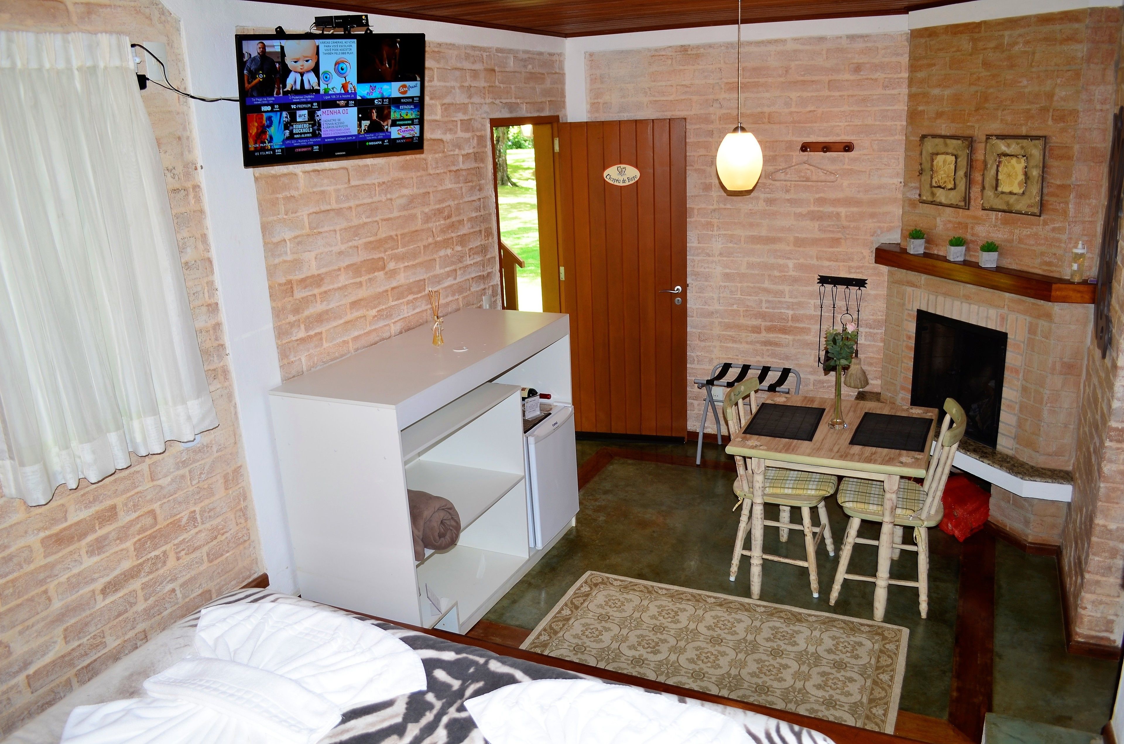 A cozy room with a brick wall, a wooden door, a small dining table, and a fireplace.