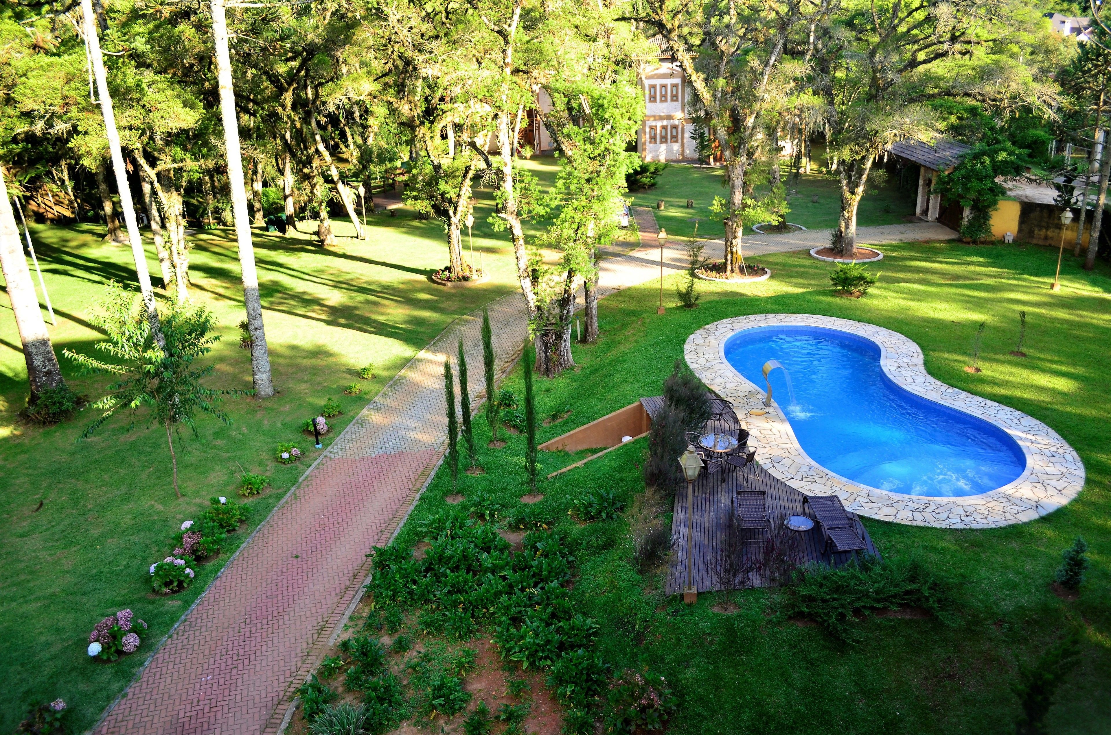 Un giardino sul retro con una piscina, un vialetto in mattoni e un pontile in legno.