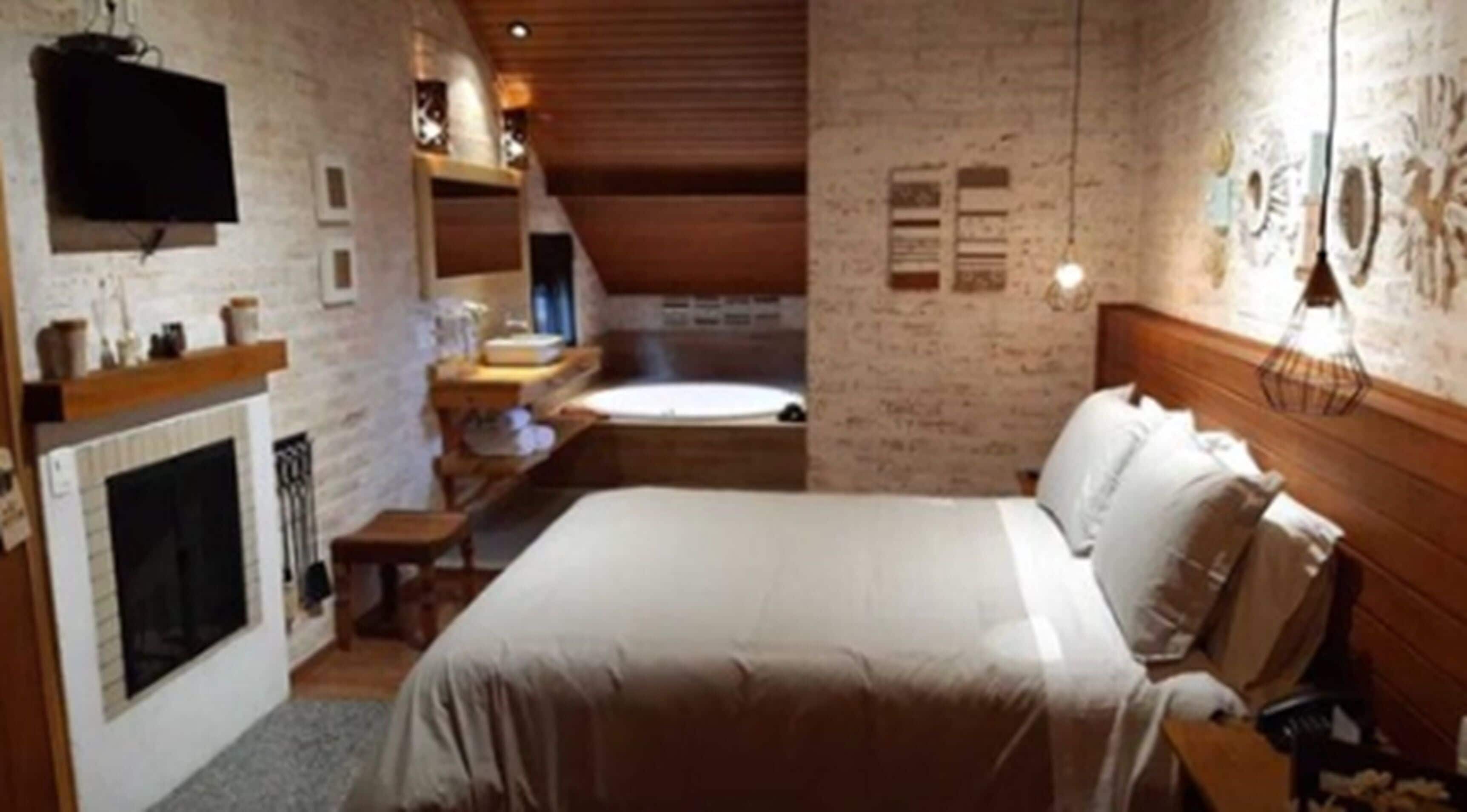 Ein Schlafzimmer mit einem großen Bett, einem Kamin und einem an der Wand befestigten Fernseher.