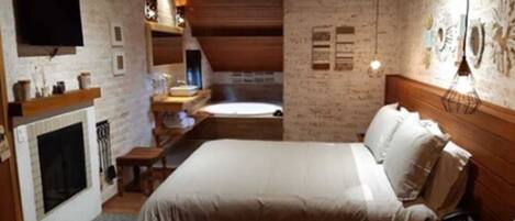 A bedroom with a large bed, a fireplace, and a television on the wall.