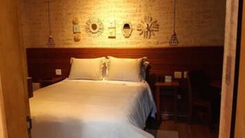 A neatly made bed in a room with a wooden headboard and a brick wall.
