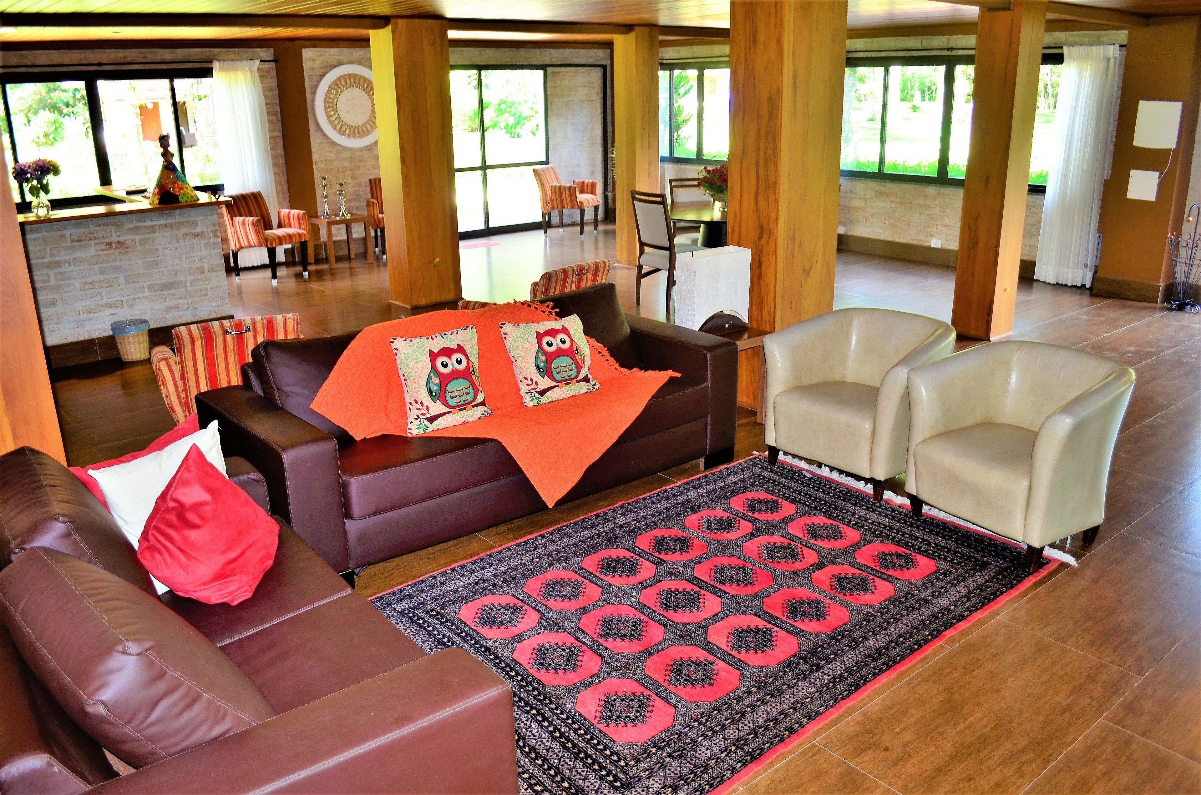 A spacious lobby with leather sofas, a patterned rug, and a view of the outdoors through large windows.