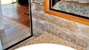 Un baño con una bañera grande, una puerta de madera y vistas a un jardín a través de una ventana.