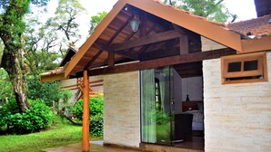 Una casa moderna con techo de madera, un ventanal de vidrio que da a un dormitorio y un jardín con un columpio de madera.