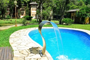Una piscina al aire libre de temporada, sombrillas