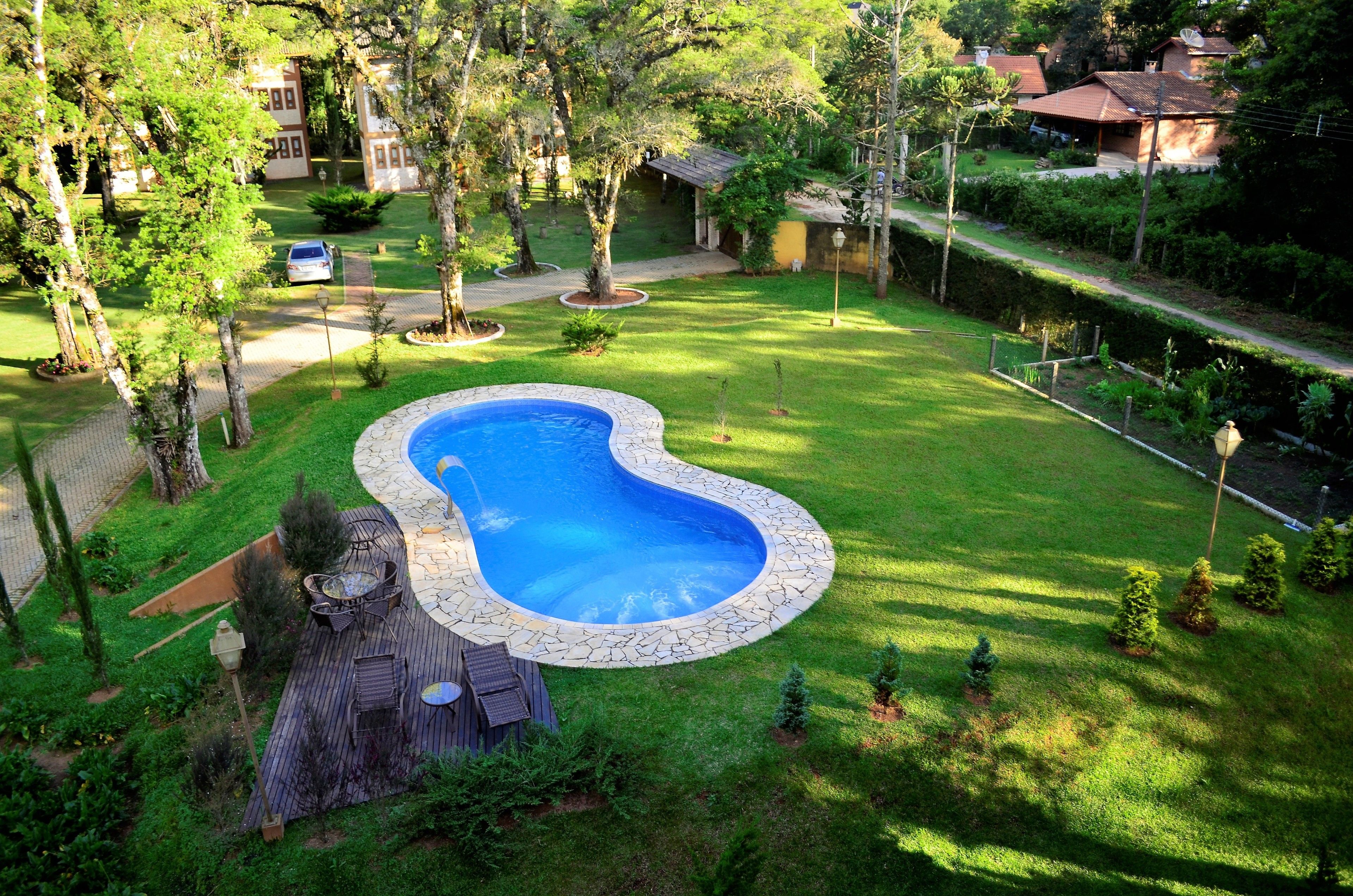 A backyard with a swimming pool, surrounded by a well-maintained lawn and trees.