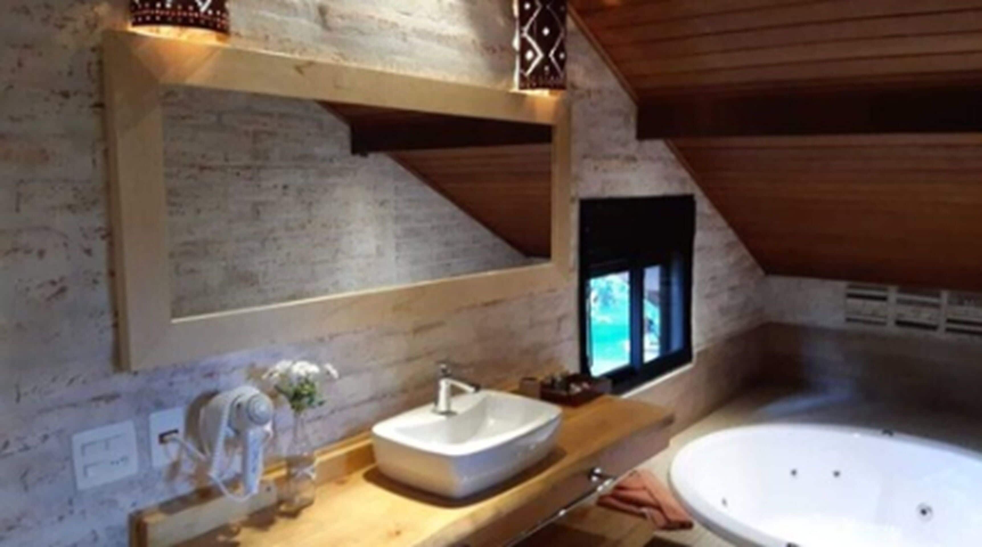 A bathroom with a wooden vanity, a white sink, and a bathtub.
