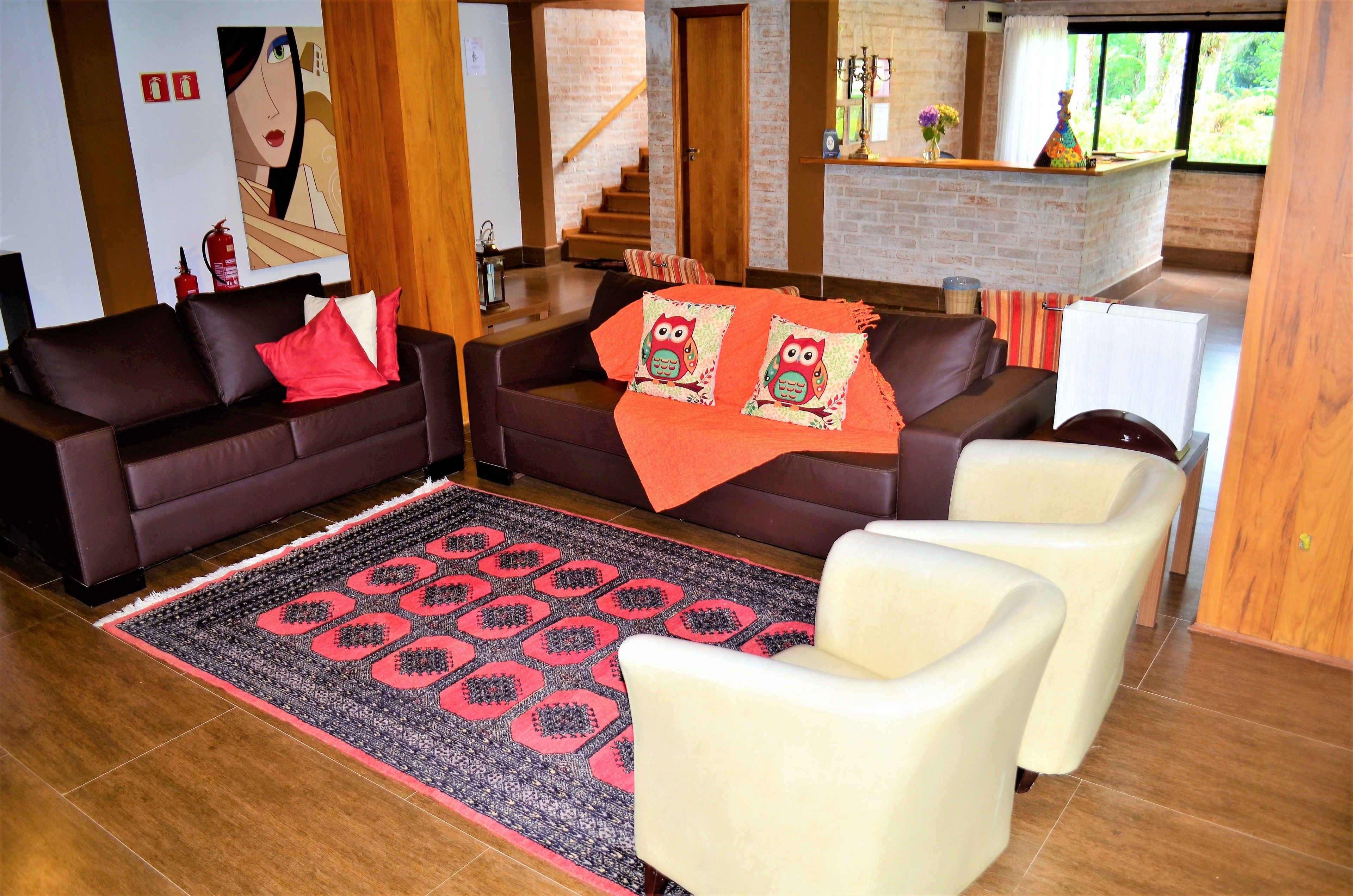 Un salon moderne avec deux canapés, un tapis à motifs et un escalier menant à une cuisine.