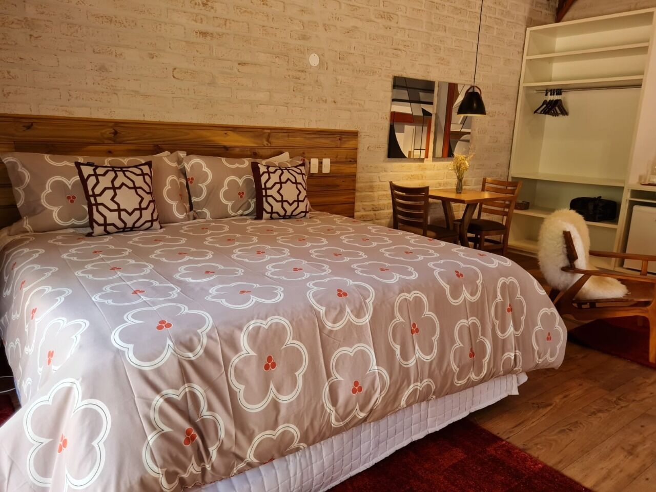 Un dormitorio con una cama grande, un cabecero de madera, una mesita de noche con un jarrón y una silla.