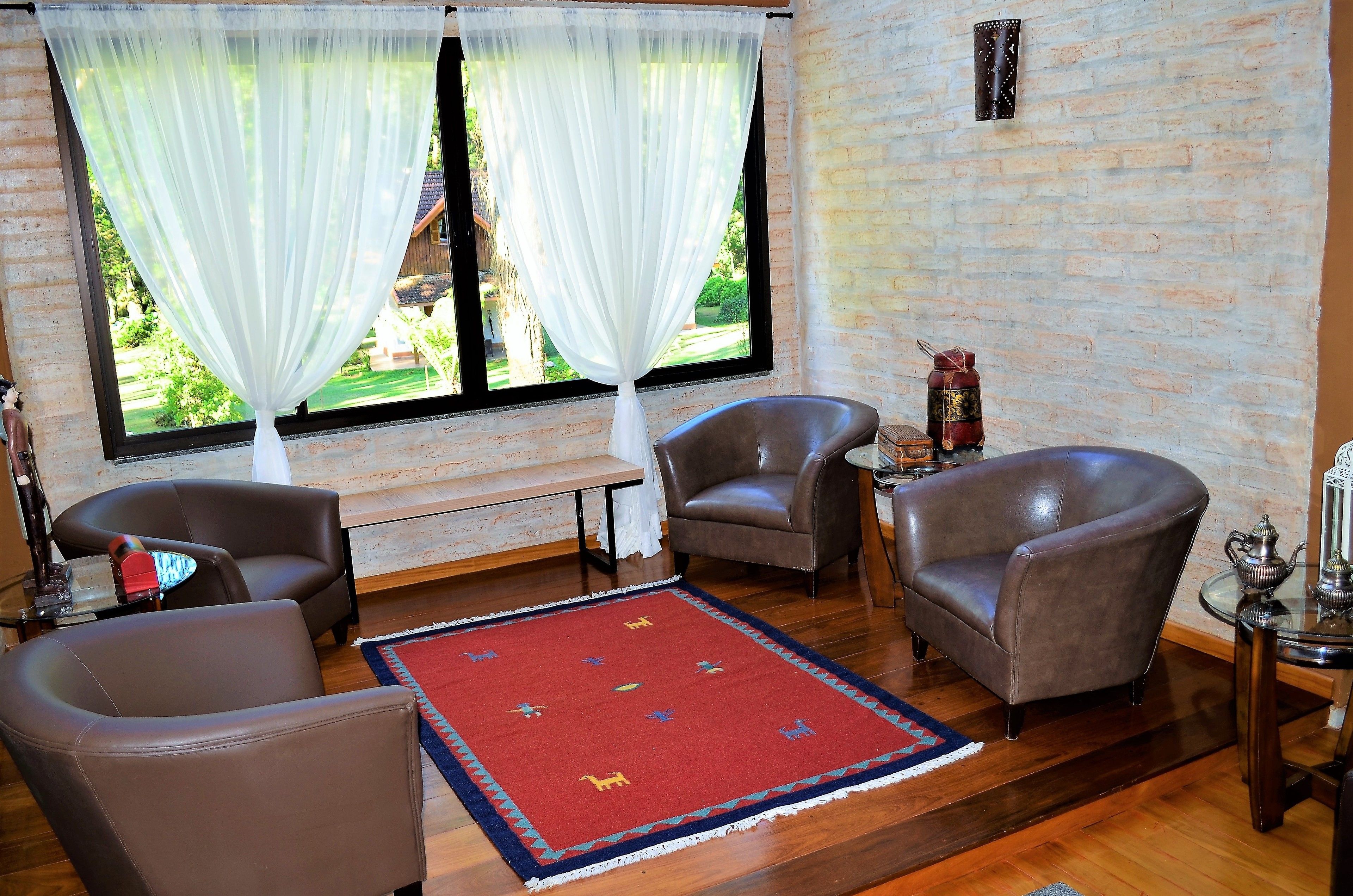 Una habitación con dos sillones de cuero, una mesita y un tapete rojo con estampados de animales.