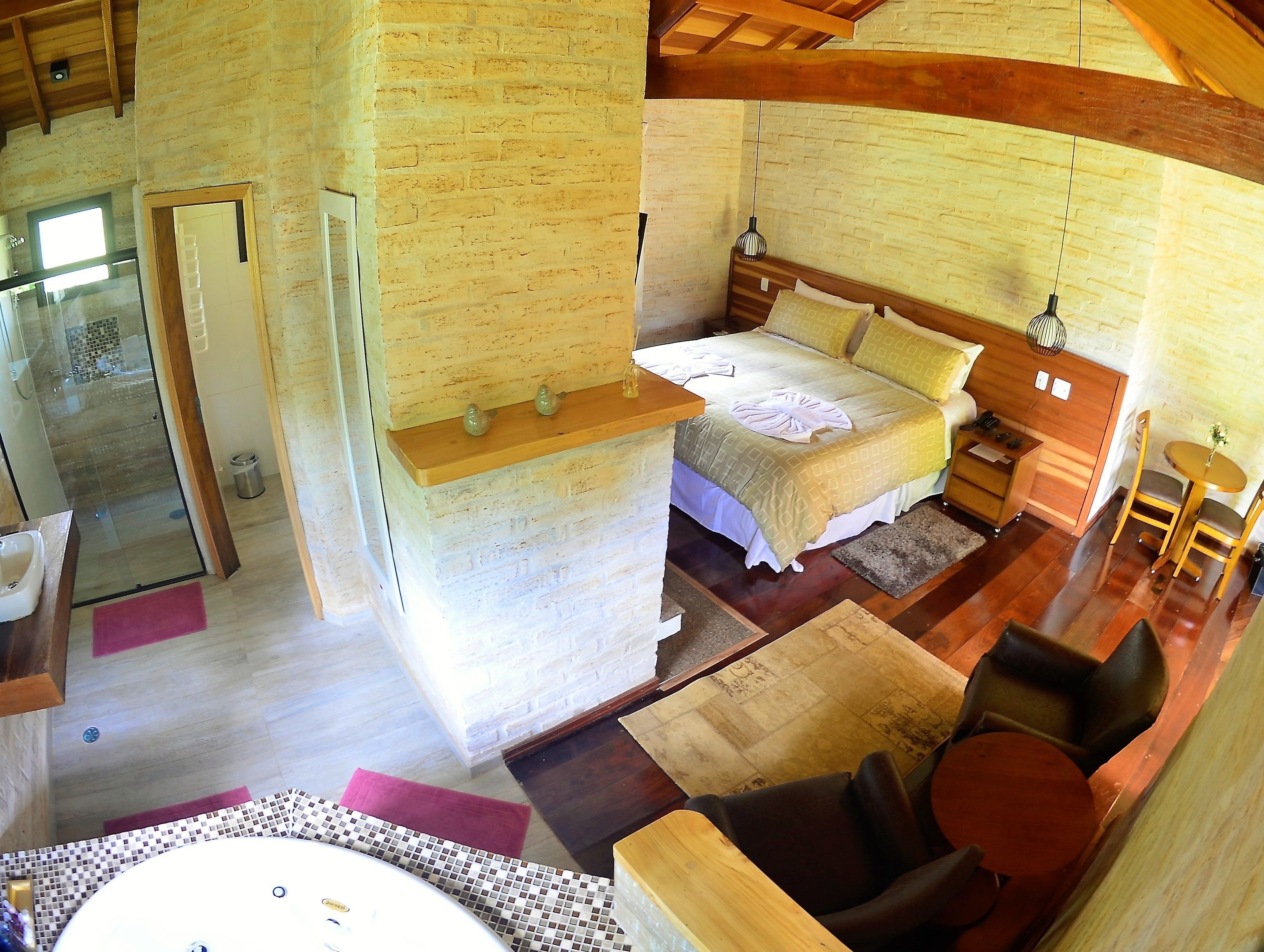 Une pièce confortable avec un lit, une petite table et une chaise. Il y a une fenêtre et une porte qui donne sur une autre pièce.