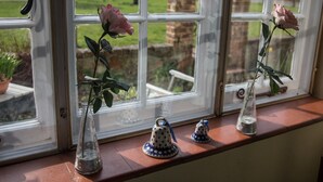 A window with a rose in a glass vase and two bell-shaped vases on a ledge. - The Old Manor House B & B (Westerham)