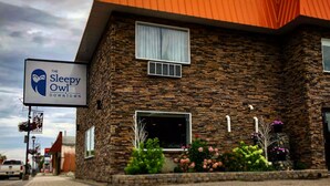 A building with a stone facade and an orange roof, featuring a sign for 'The Sleepy Owl Downtown'. - The Sleepy Owl (Fort Frances)