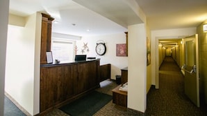A reception area with a wooden desk, a clock, and a framed picture on the wall. A carpeted hallway leads to a door. - The Sleepy Owl (Fort Frances)