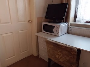 A room with a white desk, a computer monitor, a microwave, and a patterned chair. - Jaylets Budget Hathern (Loughborough)