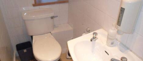 A small bathroom with a toilet, sink, and a window above the toilet.