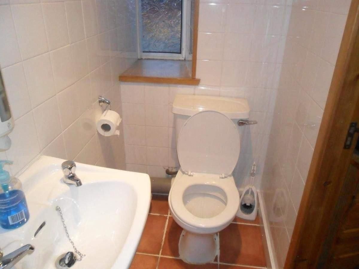 A bathroom with a white toilet, a sink with a faucet, and a window above the toilet.
