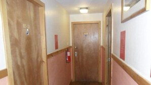 Un pasillo estrecho con puertas de madera y paredes rosadas.